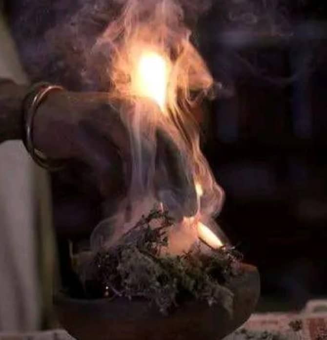 Herbs burning in a clay pot during a traditional ritual